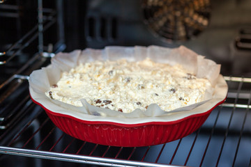 raw dough for cottage cheese casserole in a round ceramic form in the oven
