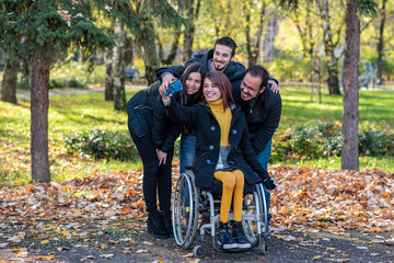 Young disabled woman in a wheelchair taking selfie with friends in a park
