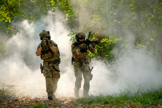 Two soldiers with the fighting uniform walk on the ground and point gun to enemy for the concept of battle in war.