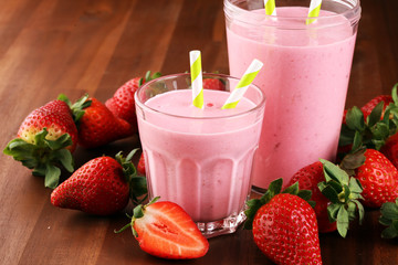 Glass of fresh strawberry shake, smoothie or milkshake and fresh strawberries on table. Healthy food and drink concept