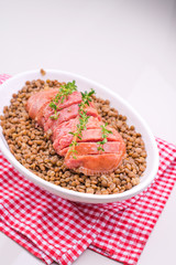 Italian large pork sausage cotechino served with lentils. Traditional Christmas dishes of Italy. A bowl of food on a plate