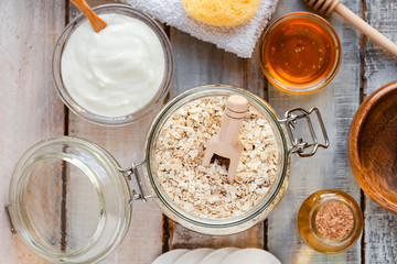 Concept of natural organic ingredients in cosmetology and gentle home treatment in quarantine. Do it yourselft. Handmade mask with oat, honey, yogurt. Wooden background. Flat lay top view close up