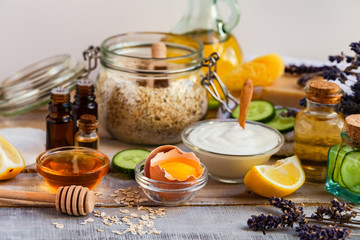Concept of natural organic ingredients in cosmetology, home treatment in quarantine. Do it yourselft. Handmade mask with honey, egg, oat, lemon, cucumber, essential oils. Wooden background top view 