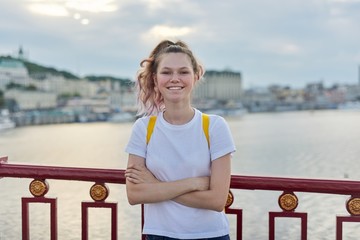 Outdoor portrait of smiling teenage girl of 15, 16 years old with folded arms