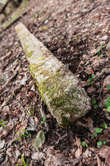 An old concrete pillar fell. Concrete covered with moss. Ruins in the forest.