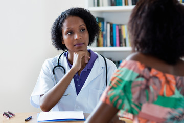 Mature african american female doctor listening to patient with pain and coronavirus symptoms