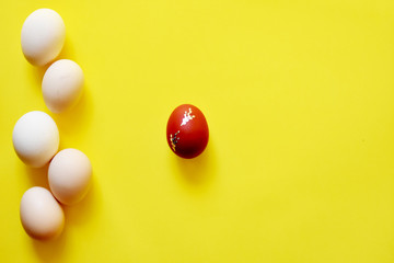 White Easter eggs on yellow background with one egg on red color