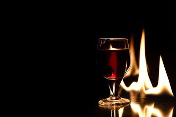 red drink cup with fire behind and reflection on black background.