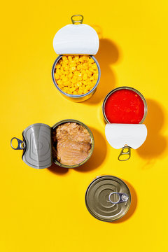 Overhead view of open canned goods isolated against yellow background.