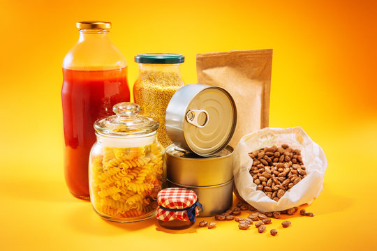 Stockpiling food concept. Various groceries on top of yellow background.