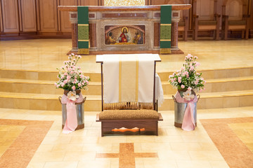 Flowers setup by a kneeler on altar in a catholic church.