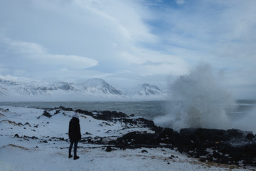 Woman standing at shore of Búðir looking at crashing waves, Snæfellsnes Peninsula, Iceland