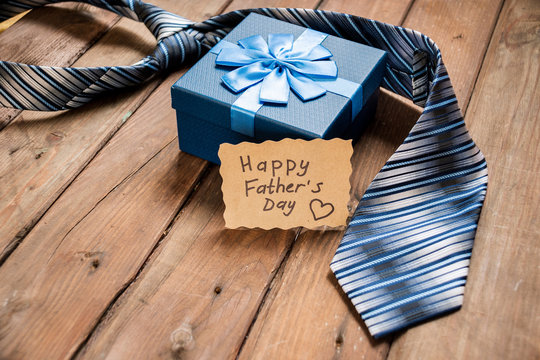 Happy Fathers Day gift box with tie on a rustic wood background. - Powered by Adobe