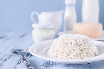 Fresh cottage cheese close-up. In the background a set of dairy products. Photo in light blue tones with copy space.
