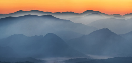 silhouettes of foggy mountains. picturesque mountain peaks at sunrise.