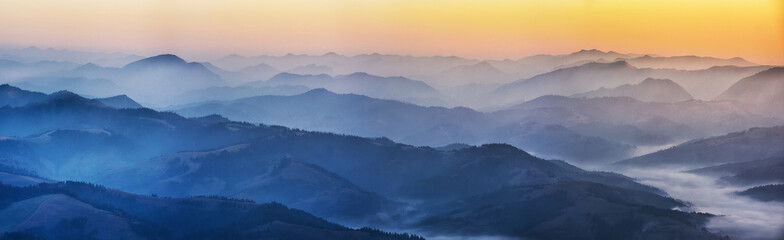 Fototapeta na wymiar silhouettes of foggy mountains. picturesque mountain peaks at sunrise.