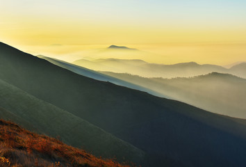 silhouettes of foggy mountains. picturesque mountain peaks at sunrise.
