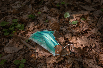 Face Mask laying on the ground in the forest. Corona virus may be on that mask.