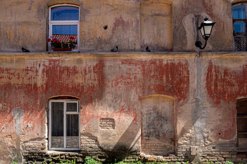 Red, dilapidated wall of an old building with windows