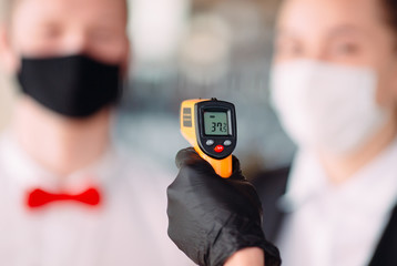The Manager of a restaurant or hotel checks the body temperature of the staff with a thermal imaging device.