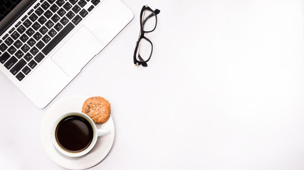 gray laptop with cup of coffee and glasses on white background table, working place at home or in the office