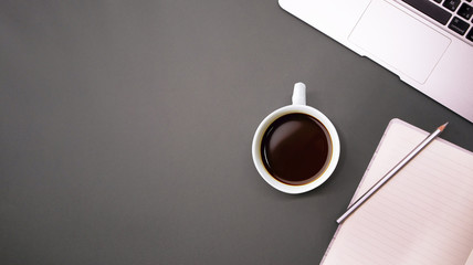 gray laptop with a notebook  and glasses on  dark gray background table, working place at home or in the office