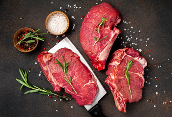raw beef steaks with spices, raw steak on a knife on a stone background