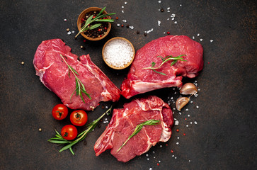 raw beef steaks with spices, raw steak on a knife on a stone background