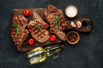 three grilled beef steaks with spices on a cutting board on a stone background