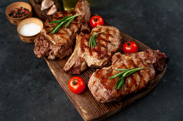 three grilled beef steaks with spices on a cutting board on a stone background