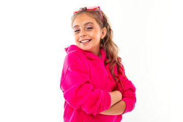 Fashionable teenager girl in pink hoody and with pink sunglasses gesticulates, portrait isolated on white background