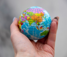 A globe in a human hand against a background of smoke.