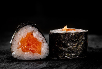 sushi roll with fish and rice in plate on black wooden table background