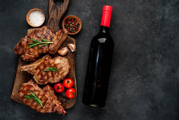 three beef steaks with grilled spices, a bottle of red wine  on a stone background   
with copy space for your text