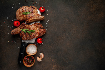 two grilled beef steaks with spices on a knife, stone background with copy space for your text