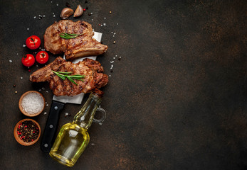 two grilled beef steaks with spices on a knife, stone background with copy space for your text