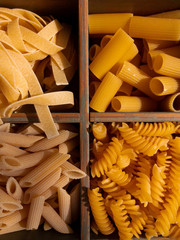 Italian pasta. Colorful pasta of various shapes lie on a wooden background. The concept of Italian pasta