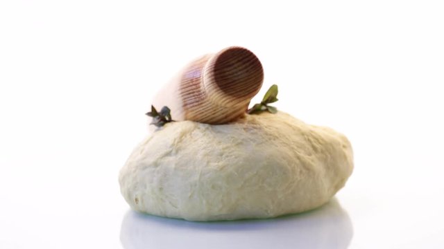 piece of raw yeast dough with a sprig of mint on a white background