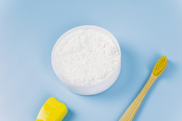 Toothbrush and dental floss and dental powder on a blue background. Oral care concept. Caring for nature, zero waste. Copyspace