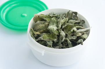 Varied varieties of flavored tea with dried mint additives. Close up. White jar with green cap