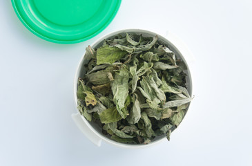 Mint drying at home, natural mint dry, large amount of mint dry in a white plastic container with a green cap. Top view