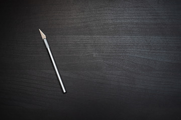 scalpel on the dark wooden table