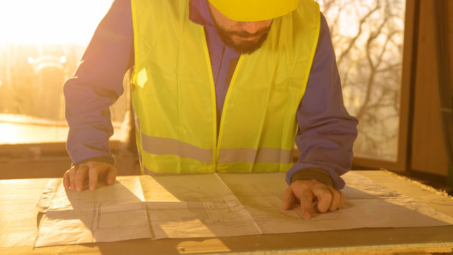 LENS FLARE: Golden evening sunbeams shine on architect looking at floor plans