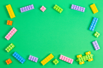 Baby kid toys background. Colorful plastic construction blocks on light green background. Top view, flat lay