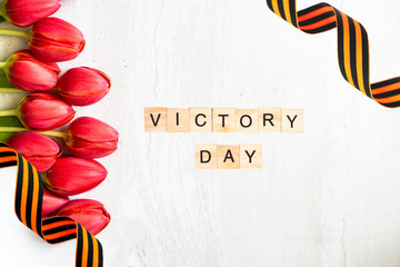 Bouquet of red tulips with St. George ribbon isolated on white background. May 9 Victory Day word.