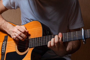 Fototapeta na wymiar A young European musician in jeans and a white T-shirt plays music on a classical guitar