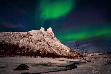 northern lights over snowcapped mountain peaks.