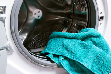 Open washing machine drum, green towel

