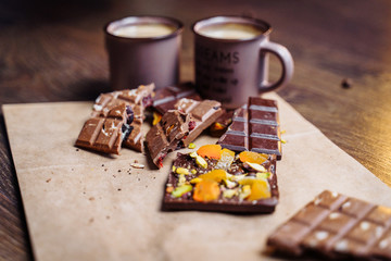Two cups of espresso coffee with grains, craft bag and chocolate on a wooden table on a dark background. Top wiev.