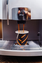 The budget model of the coffee machine prepares a delicious, fragrant espresso. Freshly brewed coffee is poured from the coffee machine into cup in the kitchen at home